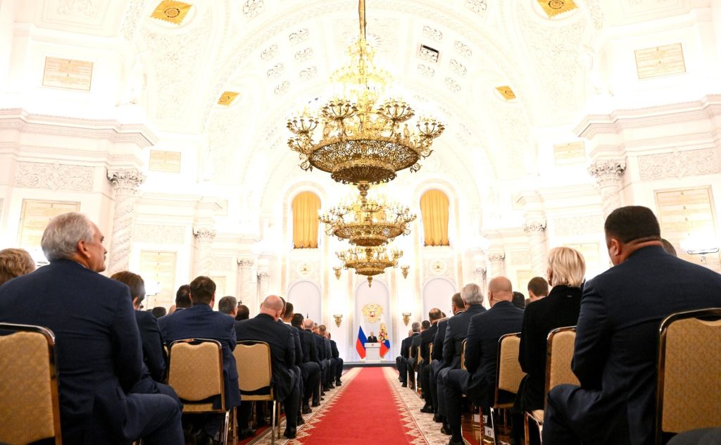  Путин накара стотиците събрали се високопоставени лица да чакат 18 минути, преди да влезе във залаta през златниte порти и на фона на звучащи фанфари. 