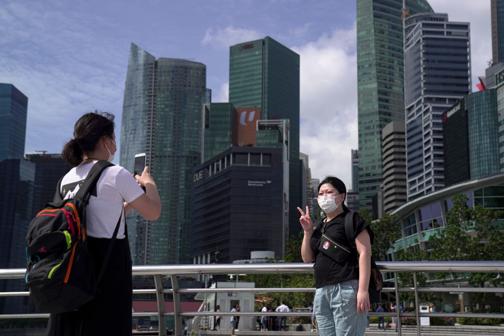 Туристи носят маски в "Мерлиън Парк" в Сингапур - място, което гъмжеше от хора преди появата на COVID-19.