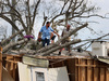 Работници отстраняват дърво от покрива на къща, паднало върху нея по време на урагана Айда през август 2021 г. в САЩ